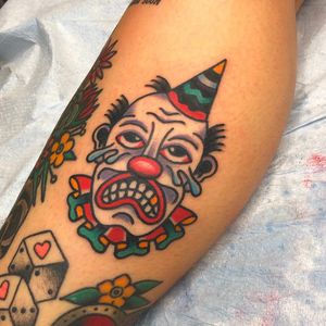 Vibrant and detailed neotraditional clown tattoo on lower leg by Nick Osbourn, featuring a whimsical hat design.