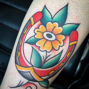 Beautiful traditional tattoo featuring a flower and horseshoe motif by Kat Freedman. Perfect for forearm placement.