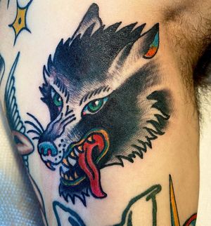 Get a fierce and timeless traditional wolf tattoo on your upper arm by the talented artist Jason Fancher. Stand out with this stunning design!