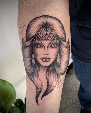 Elegant black and gray tattoo of a woman with earrings, skillfully done by Sasha Ignarski. Perfect for the forearm.