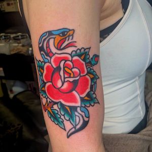 Beautiful traditional tattoo featuring a snake and flower motif, expertly done by Nick Osbourn on the upper arm