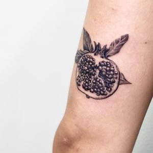 Experience the bold beauty of Juliany Braga's blackwork pomegranate design on your upper arm. A symbol of abundance and fertility.