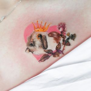 Capture the whimsy of nature with this illustrative arm tattoo featuring a rabbit, flower, and crown. Designed by Juliany Braga.