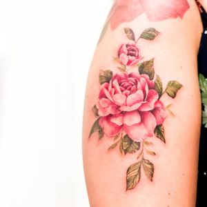 Beautiful and detailed flower tattoo on the upper arm, expertly done by artist Juliany Braga.