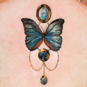 A stunning illustrative butterfly tattoo on the chest by tattoo artist Juliany Braga. Vibrant colors and intricate details bring this beautiful design to life.