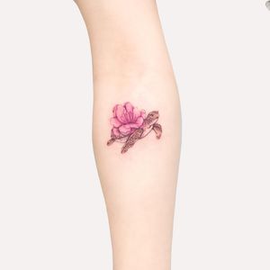 Beautiful forearm tattoo featuring a detailed illustrative design of a turtle and a flower, created by Juliany Braga.