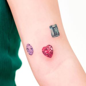 Get a stunning illustrative tattoo of a heart and crystal on your upper arm by talented artist Juliany Braga. Express your love and strength with this unique design.