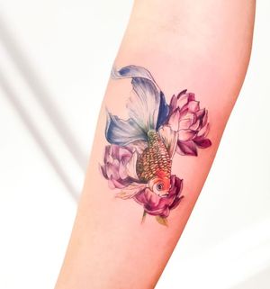 Beautiful forearm tattoo featuring a fish and flower design, created by the talented artist Juliany Braga.