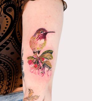 Elegantly designed upper arm tattoo featuring a beautiful bird and flower motif created by Juliany Braga.
