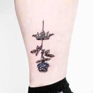 A stunning illustrative tattoo of a flower crown, expertly done in blackwork style on the lower leg by Juliany Braga.