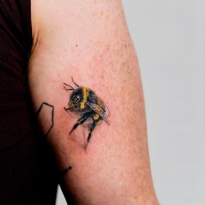 Capture the beauty of nature with a stunning bee tattoo on your upper arm by the talented artist Juliany Braga.