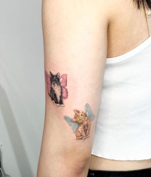 Adorn your upper arm with Juliany Braga's stunning realistic and illustrative design of a cat with wings for a mystical and unique look.