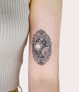 Experience the wonders of the universe with this intricate blackwork tattoo featuring a galaxy, planet, and filigree frame by Juliany Braga.