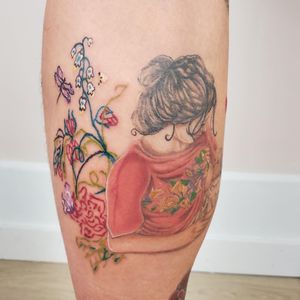 Vibrant watercolor tattoo featuring a butterfly, flower, and woman done by Maritana Quaresma on the lower leg.