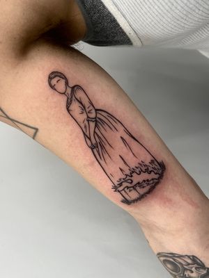 Get a stunning blackwork tattoo of a woman in a dress on your upper arm, crafted by the talented Miss Vampira.