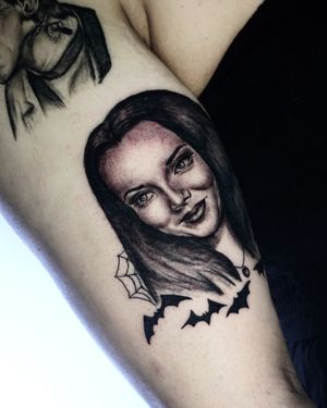 Upper arm tattoo featuring a bat, spider, and woman in blackwork and realism style by Miss Vampira.