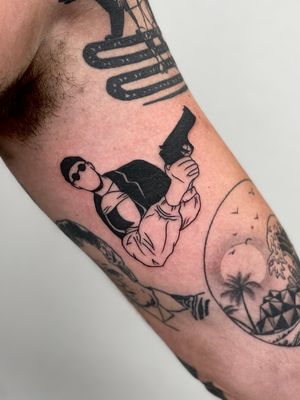 Unique upper arm tattoo by Miss Vampira featuring a man and girl wearing glasses, with a gun and a lion. Bold blackwork style.