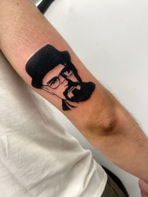 Get inked with the iconic image of Bryan Cranston as Walter White from Breaking Bad. Illustrative blackwork tattoo by Miss Vampira on your upper arm.