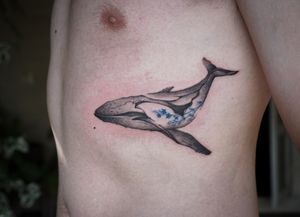 Abstract blackwork whale tattoo with blue flowers by Thai tattoo artist in Chiang Mai, Thailand