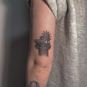 A unique blackwork tattoo on the upper arm featuring a star and building motif, created by the talented artist Amour.x.