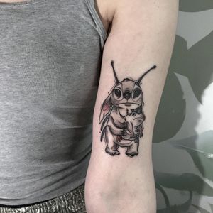 Emiliia Kuzmina's illustrative design on upper arm blends frog motif with stitch details for a bold and unique tattoo.