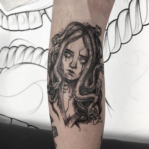 Blackwork illustrative tattoo featuring a woman and a snake, done by Emiliia Kuzmina on the lower leg