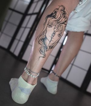 Elegant illustrative blackwork design on lower leg by Greed, featuring intricate patterns and a mysterious girl motif.