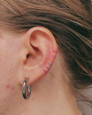 A vibrant and intricate rainbow pattern adorning the ear, expertly executed in a whimsical watercolor style by the talented artist Silber/Sofie.