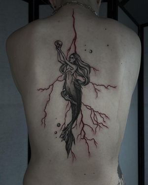 Emiliia Kuzmina's illustrative back tattoo features a striking design of skull, pattern, and woman in bold blackwork style.
