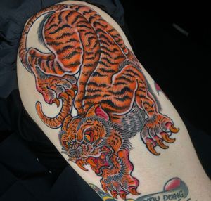 Experience the power and grace of a Japanese tiger in this striking upper arm tattoo by renowned artist Matthew Ono.