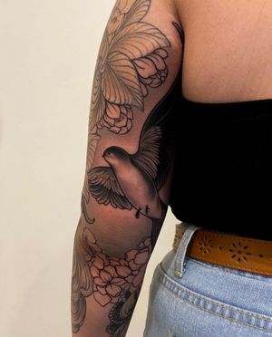 Experience the elegance of a black and gray bird tattoo expertly inked by Edyta on your upper arm. Embody freedom and beauty.