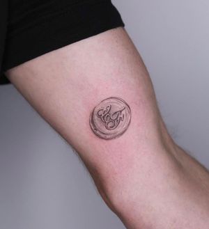 Unique upper arm tattoo combining lettering and realism with an illustrative coin motif, expertly crafted by tattoo artist Oscar Jesus.