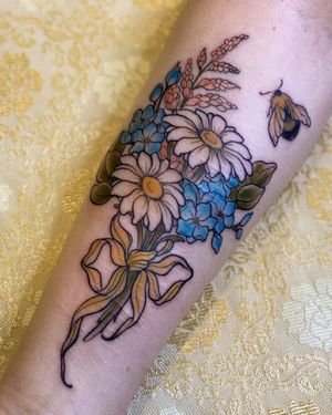 A stunning neo-traditional tattoo of a bee and flower, expertly done by Edyta, beautifully placed on the forearm.