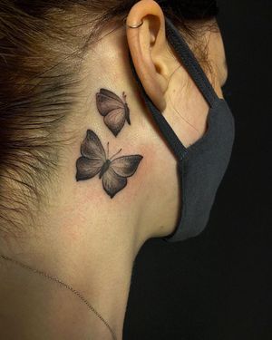 Witness the beauty of a black and gray butterfly motif delicately tattooed on the neck by the talented artist Edyta.