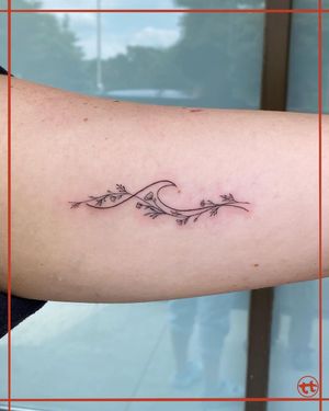 Get mesmerized by Tianna's delicate fine line design featuring a beautiful wave and flower motif, perfect for your arm.