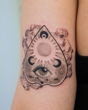 Beautiful blackwork design on upper arm by tattoo artist Yasmin Clara, featuring moon, eye, filigree, and ouija elements.