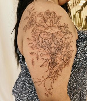 Elegant blackwork design by Palena featuring a delicate moth and intricate flower motif on the upper arm.