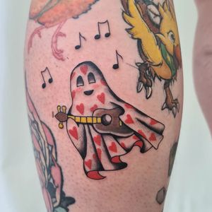 Get inked with a unique lower leg tattoo featuring a heart, music notes, guitar, and ghost in illustrative style by Liza Vettaa.