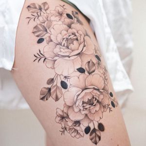 Elegant blackwork floral design by Yasmin Clara, perfectly placed on the upper leg for a bold statement.