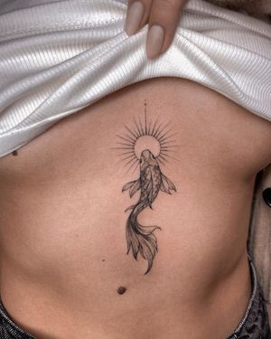 A striking blackwork piece by artist Irene Bogachuk, featuring a sun, fish & intricate patterns on the stomach.