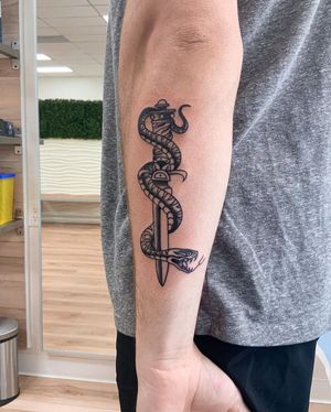 Discover the fierce combination of a snake and dagger in bold blackwork style by artist Steven Brooks. Perfect for your forearm!