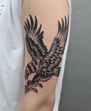 Get inked with a fierce eagle design on your upper arm by the talented artist Liza Vettaa. Embrace the power and symbolism of this striking blackwork tattoo.