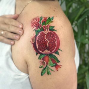 Experience the beauty of nature with this illustrative upper arm tattoo by Daniel Verdysh. Featuring a vibrant pomegranate and flower design.
