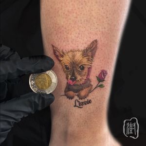 Beautiful ankle tattoo featuring a dog, flower, and name in stunning lettering style by the talented artist Cerf.