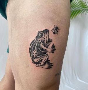 Get a striking blackwork tattoo of a frog hunting a fly on your upper leg. Unique design by Jenna Jeep.
