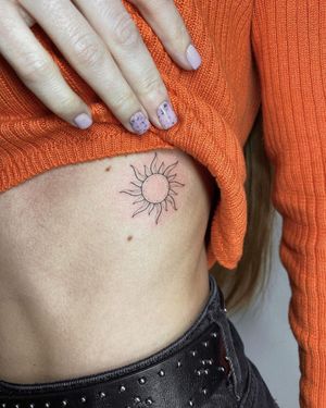 Irene Bogachuk's detailed blackwork sun tattoo shines bright on the ribs, blending fine line and illustrative styles seamlessly.