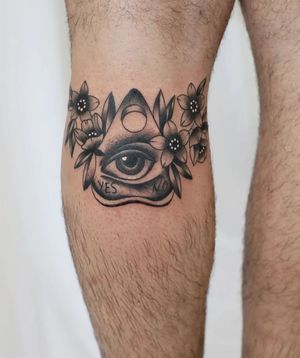 Get a stunning blackwork tattoo featuring a flower, ouija board, and eye on your lower leg by the talented artist Liza Vettaa.