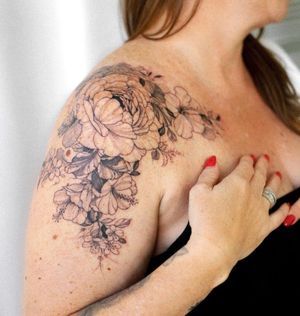 Elegant blackwork flower tattoo on shoulder, designed by Sasha Sunshine for a timeless and artistic look.