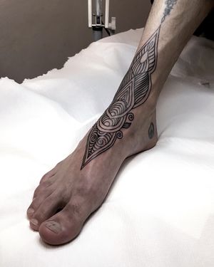 Get a unique blackwork tribal pattern tattooed on your foot by the talented artist Juli Liverinova.