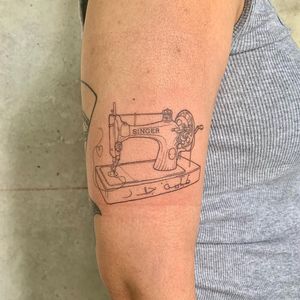 Express your love for sewing with a fine line illustrative tattoo featuring a sewing machine and inspiring quote by Holly Hawk.